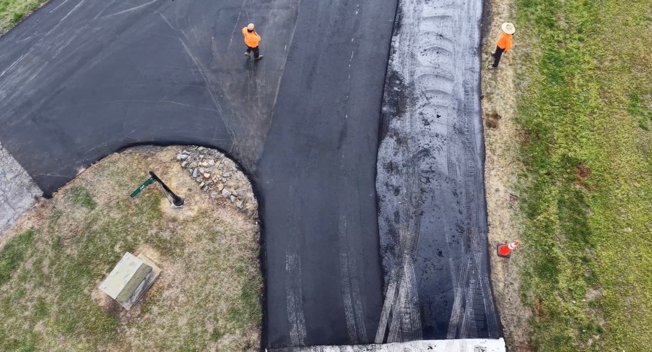 Aerial view of a Crown Paving crew placing a new asphalt surface layer over the base course