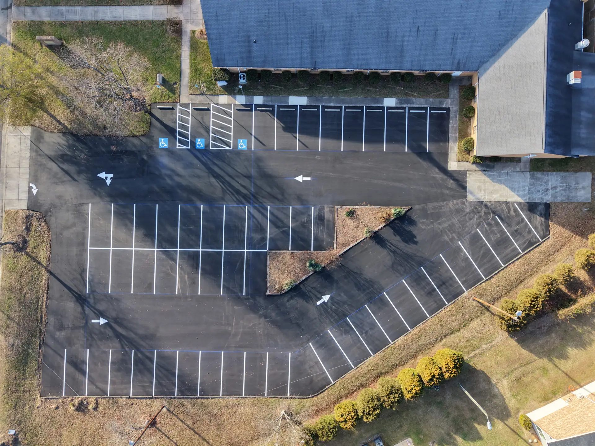 Aerial view of a freshly striped parking lot wrapping a brick building with a covered walkway