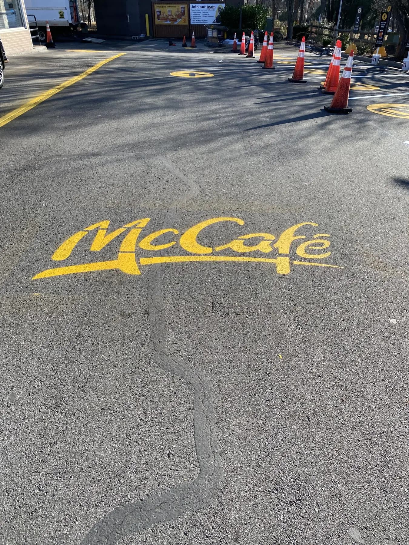 A freshly painted McCafé stencil on asphalt with traffic cones still in place
