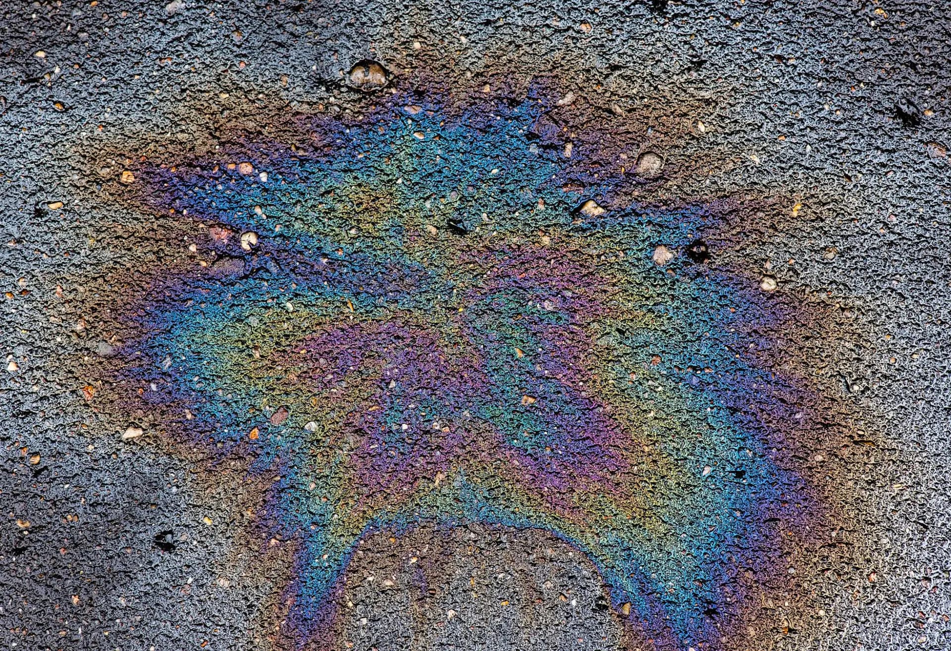 Rainbow sheen from a fuel spill sitting on an asphalt surface