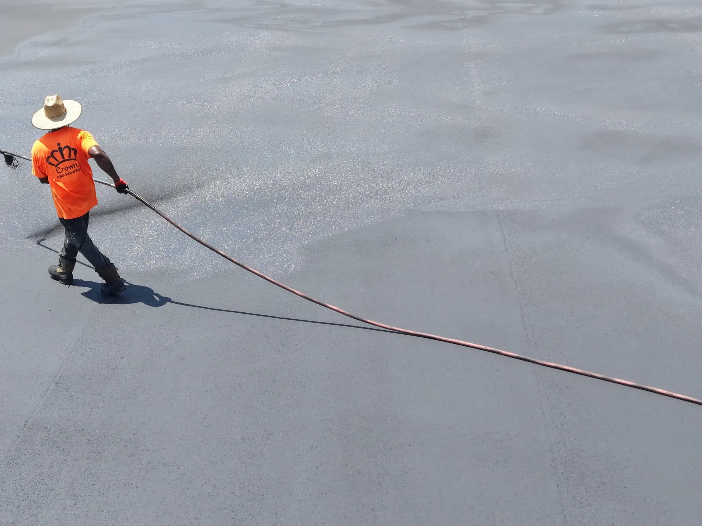 Crown Paving crew member spraying sealer across the truck yard