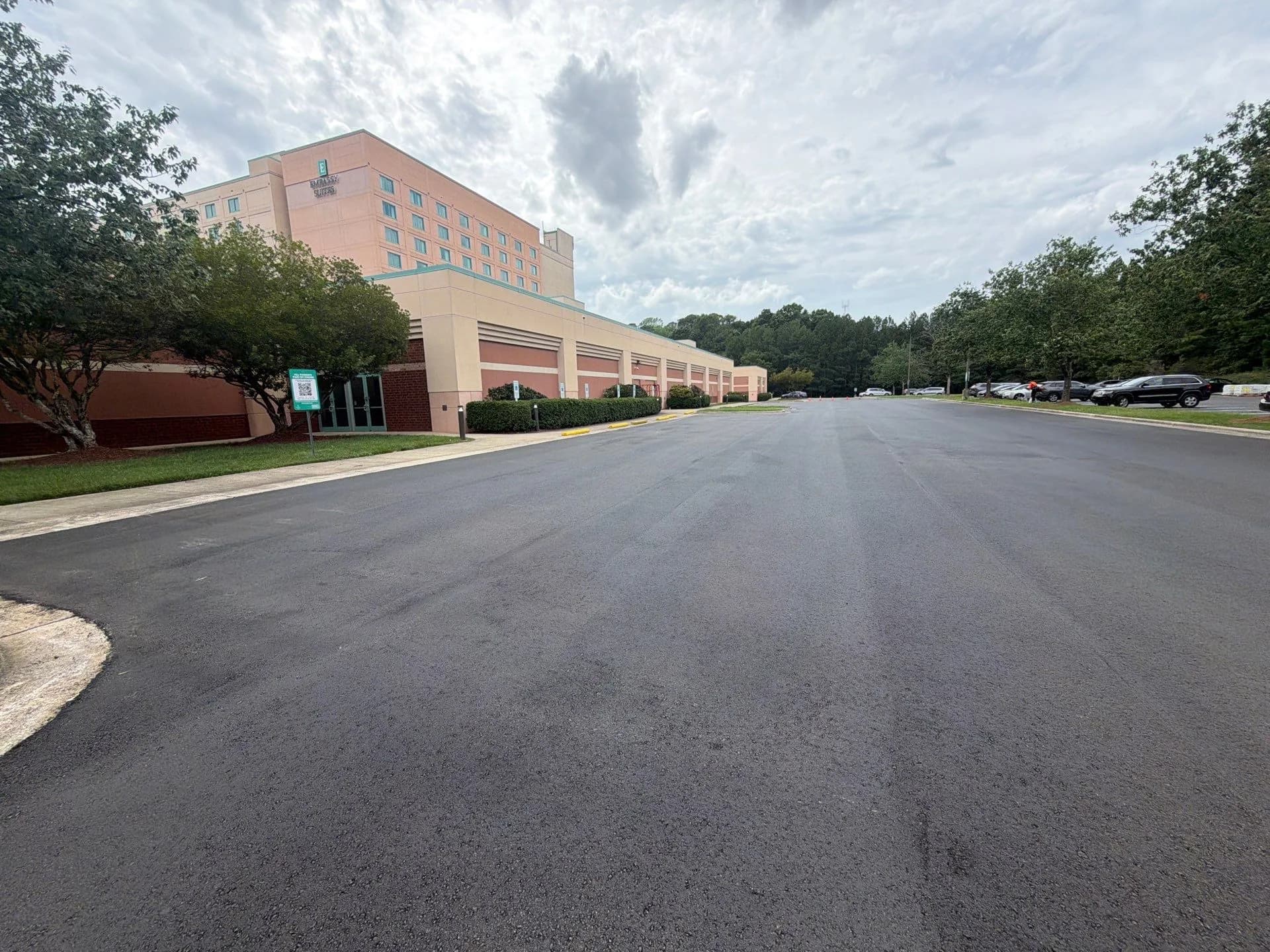 Newly paved and marked drive lane running alongside a long single-story building