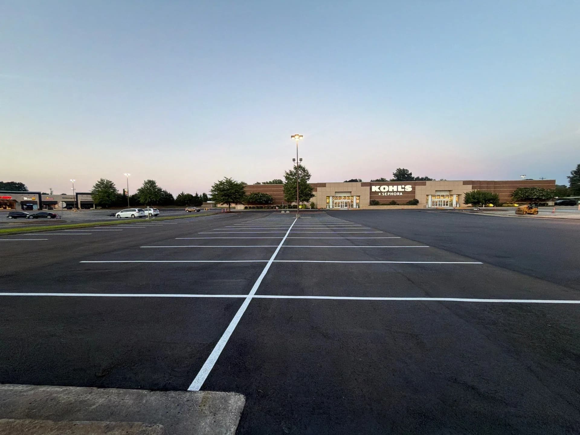 Retail parking lot at dusk with fresh striping and accessible stalls