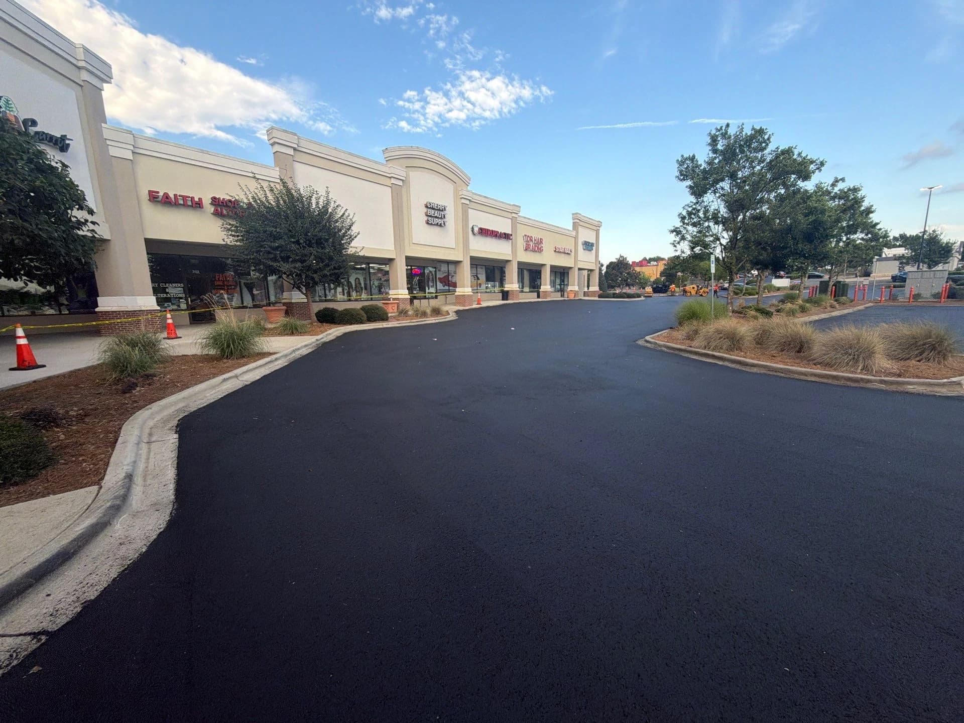 Shopping centre storefronts behind a freshly paved and striped lot
