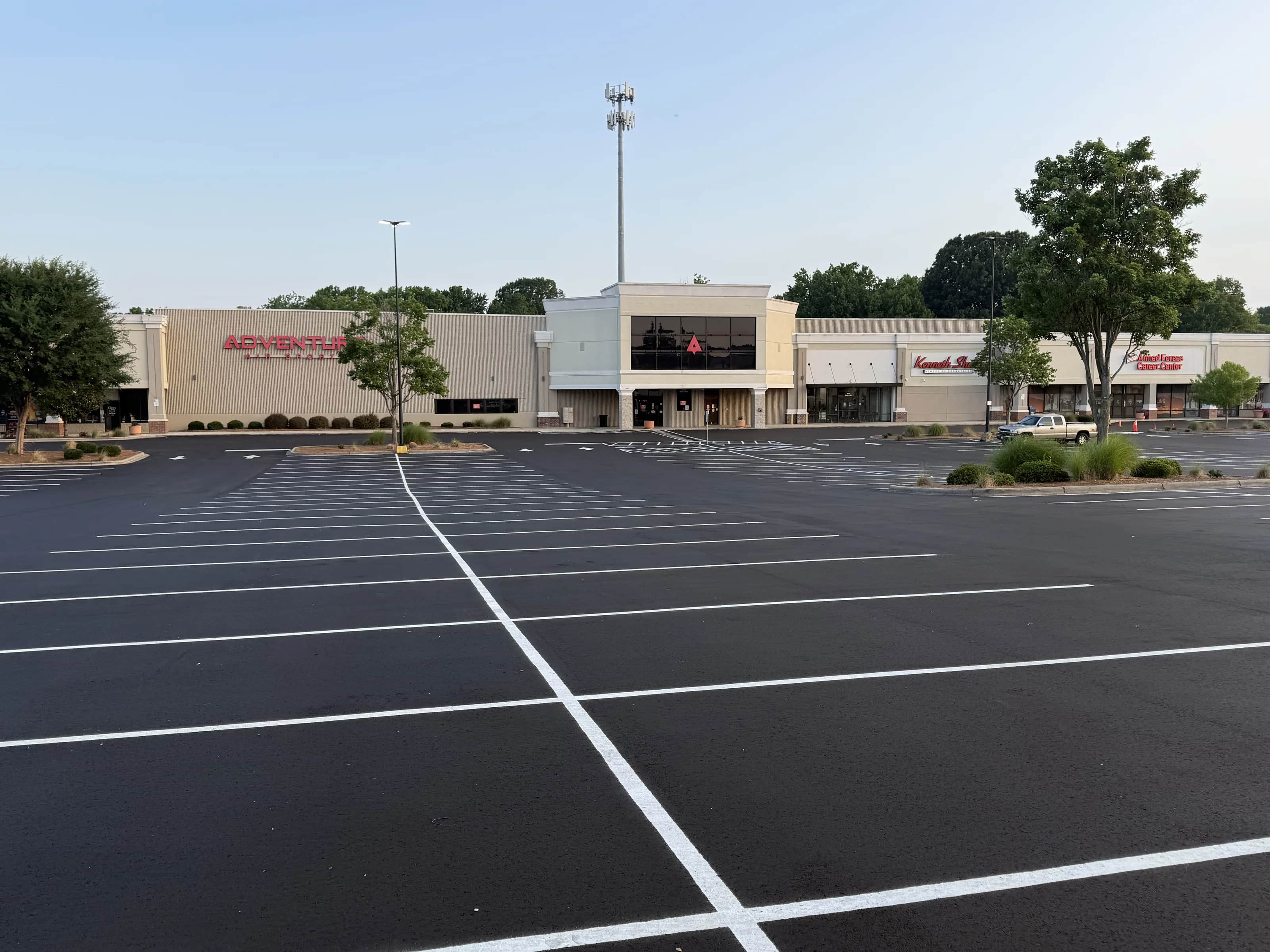 Completed retail plaza lot, freshly surfaced and striped, with the storefronts behind it
