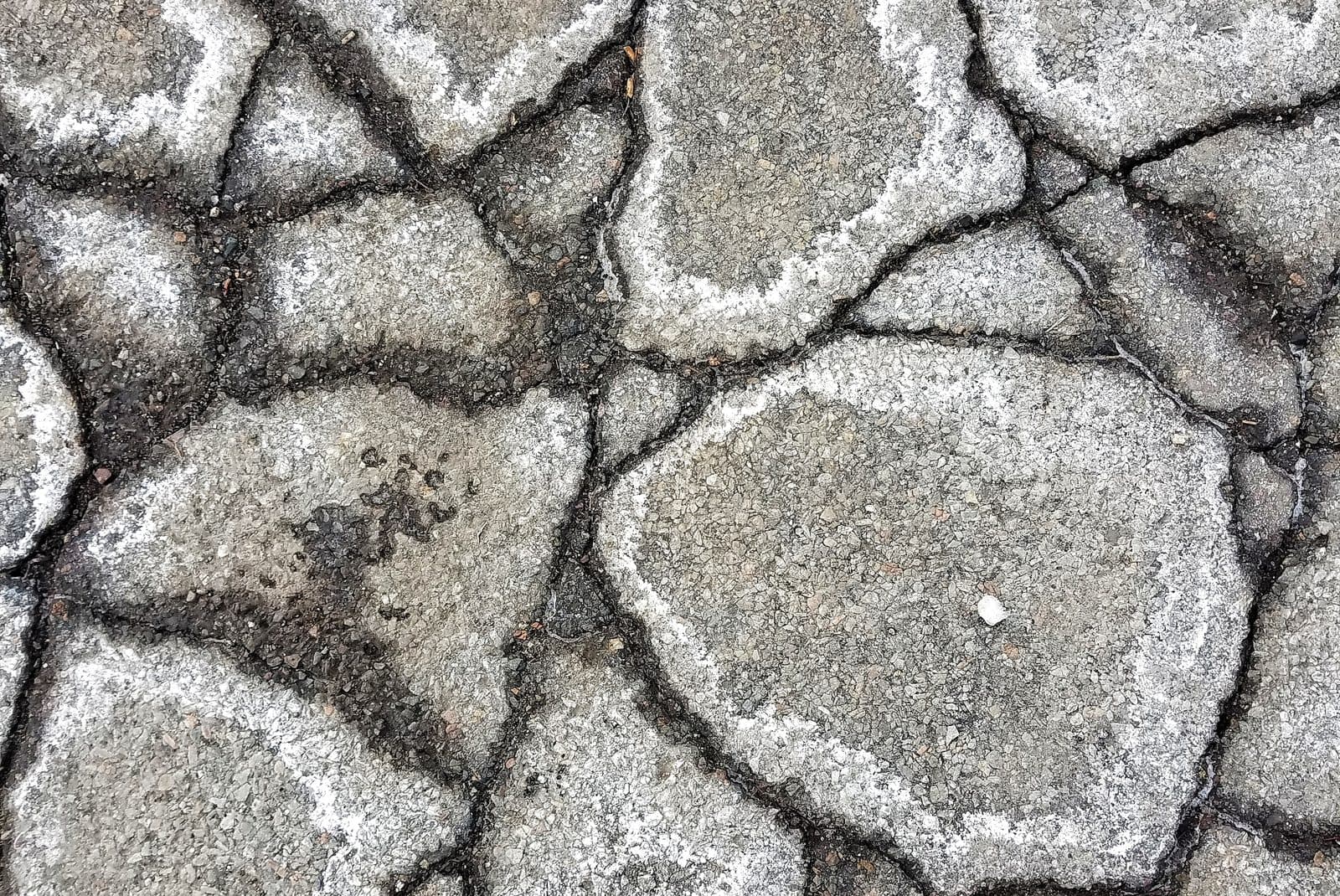 Oxidized asphalt gone gray and brittle, broken into plates by widening cracks